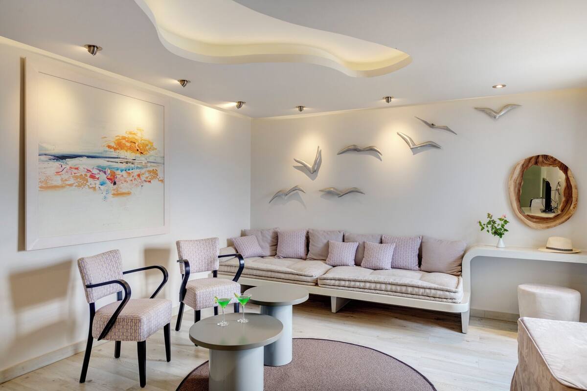Ein modernes Wohnzimmer mit einer Couch, Sesseln, einem Couchtisch und einem Gemälde an der Wand.