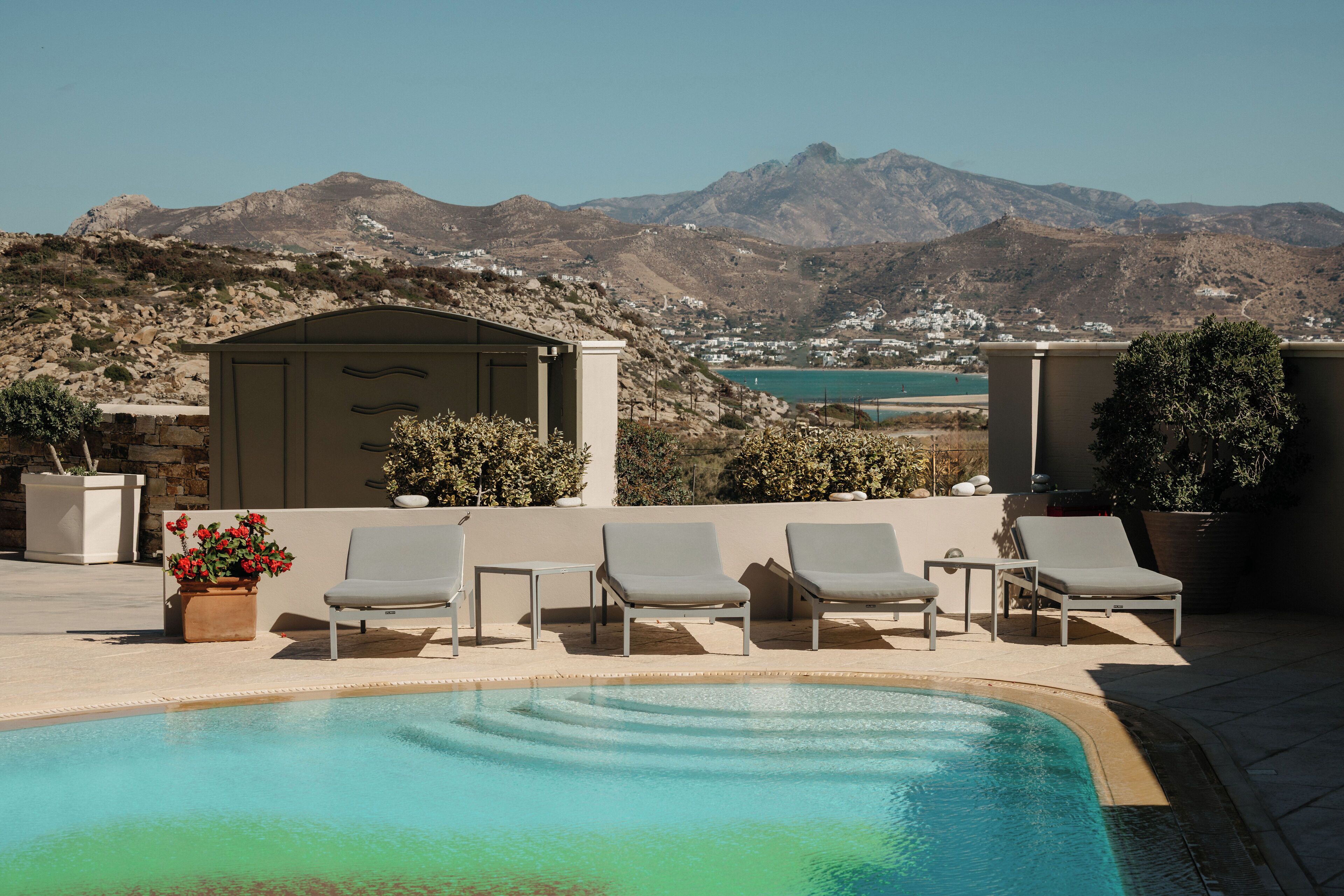 Zona de piscina con sillas de descanso y vistas a montañas.
