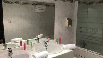 Une salle de bain avec deux lavabos, un grand miroir et une douche à parois de verre.