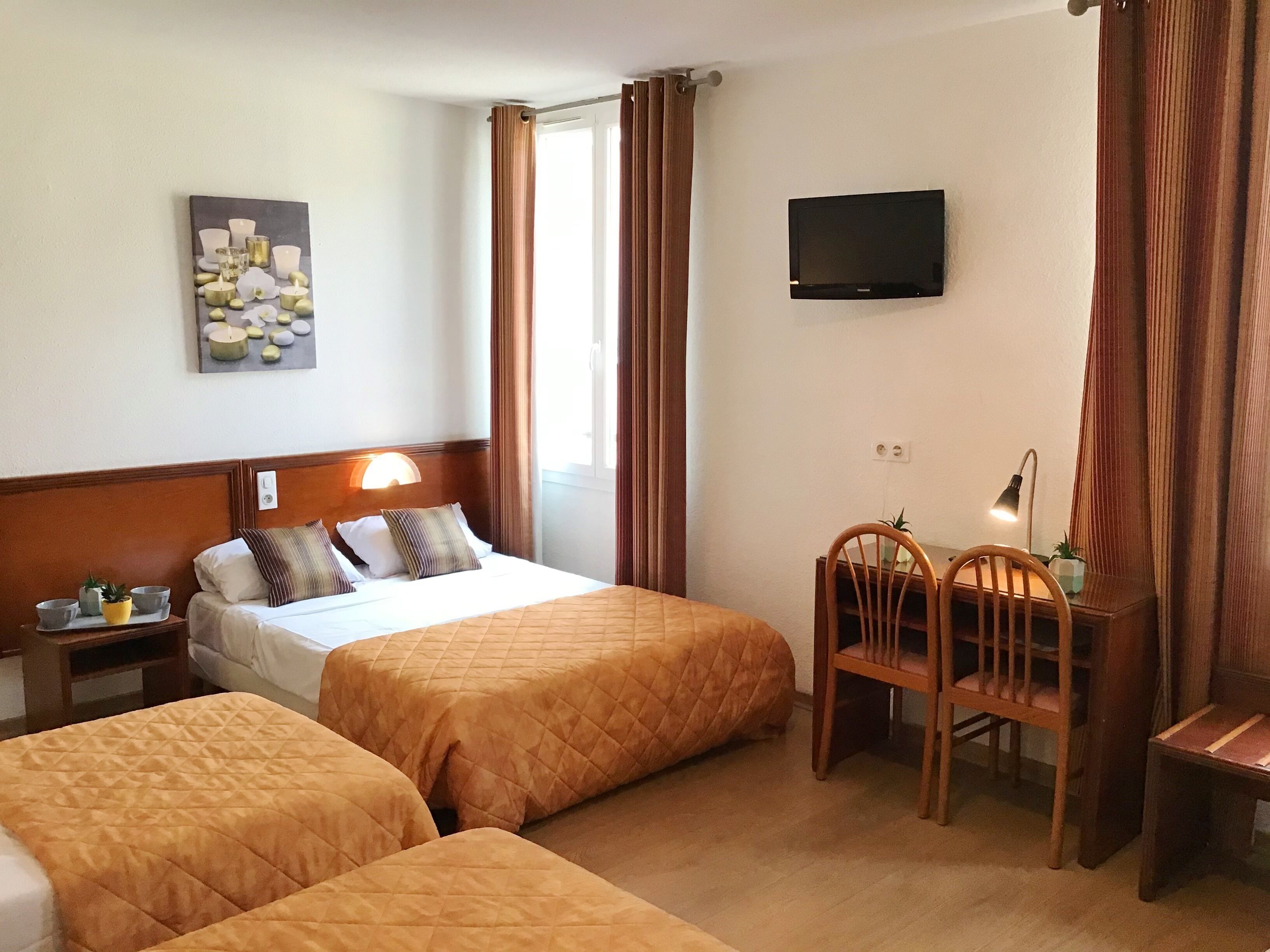 A hotel room with two beds, a desk, a chair, a TV, and a wall-mounted artwork.