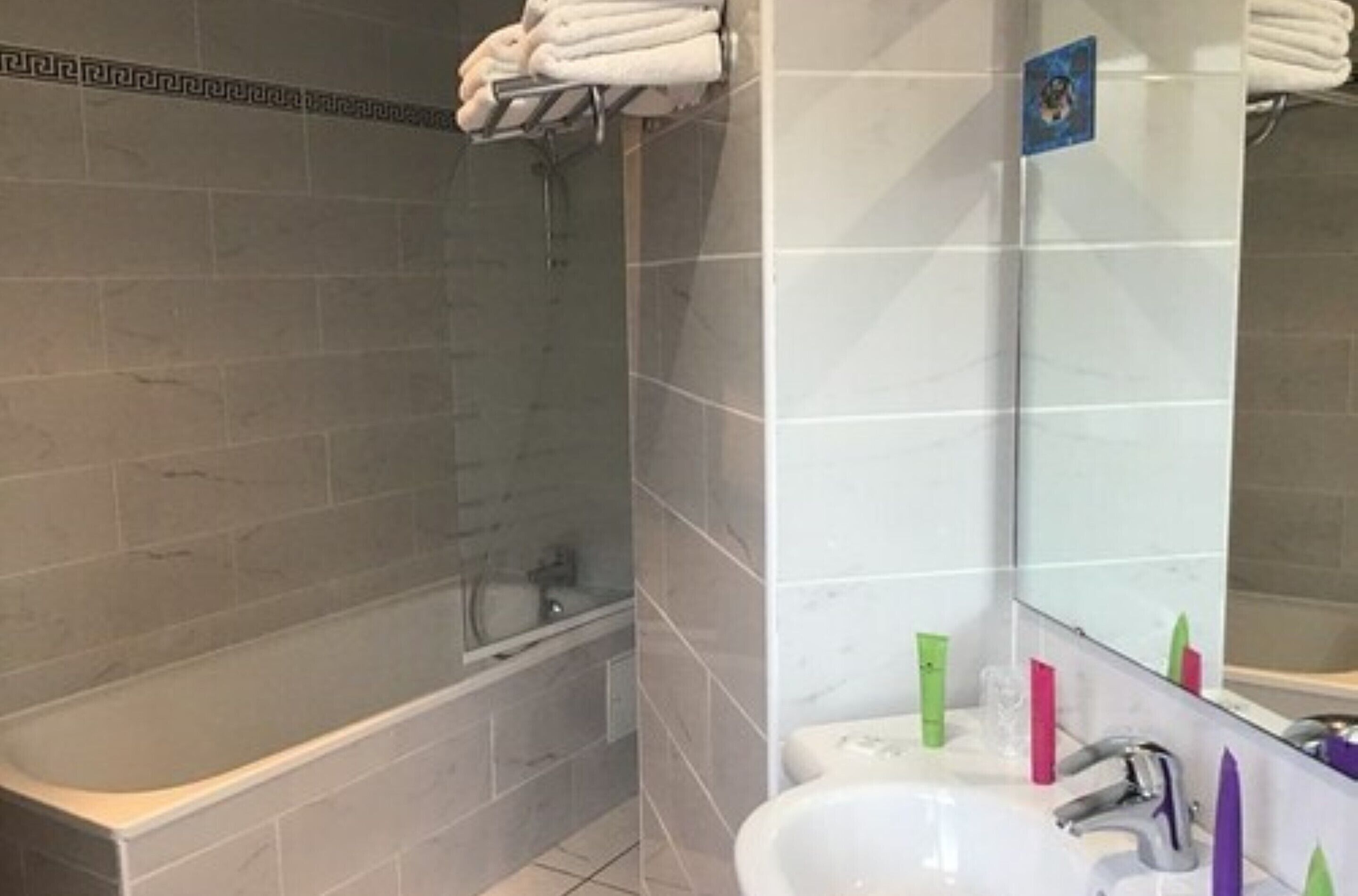A bathroom with a bathtub, a sink, and a mirror.