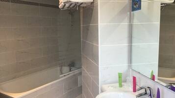 A bathroom with a bathtub, a sink, and a mirror.