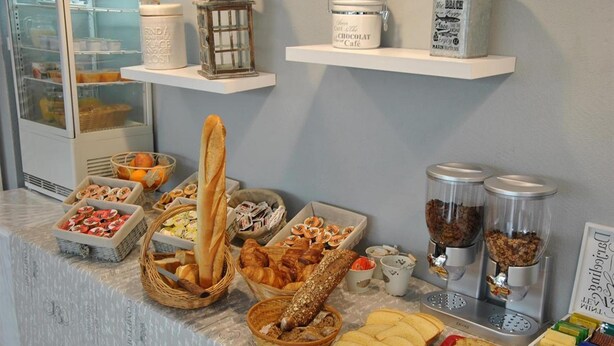 Um buffet de café da manhã com diversos pães, bolos e patês.