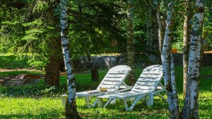 Two white lounge chairs with a table and a drink, set in a grassy area with birch trees. - Hôtel Le Carina (Gap)