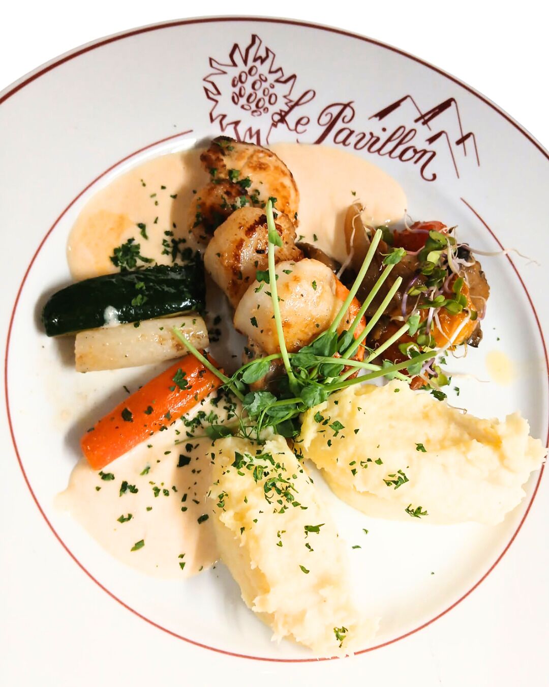 A plate of food with various vegetables and a creamy sauce.