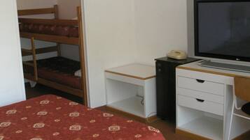 Quarto com beliches, uma escrivaninha com computador, telefone e televisão.