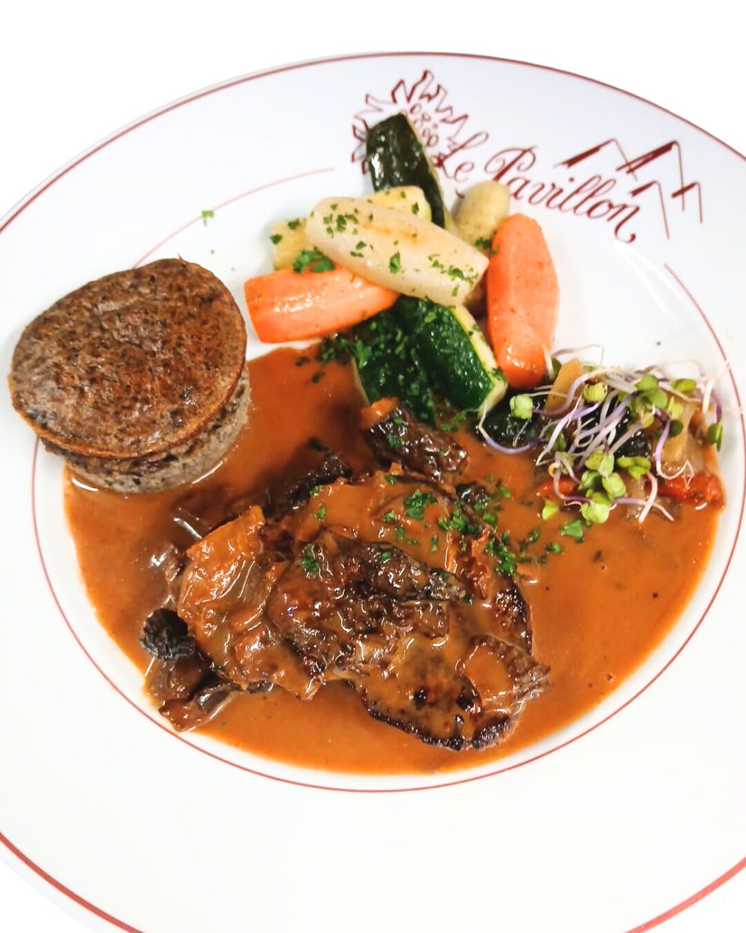 A plate of food including a steak, vegetables, and a side dish.