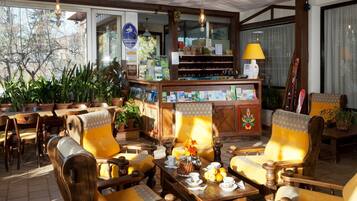 Een gezellig restaurant met houten meubels, een toonbank met diverse producten en potplanten.