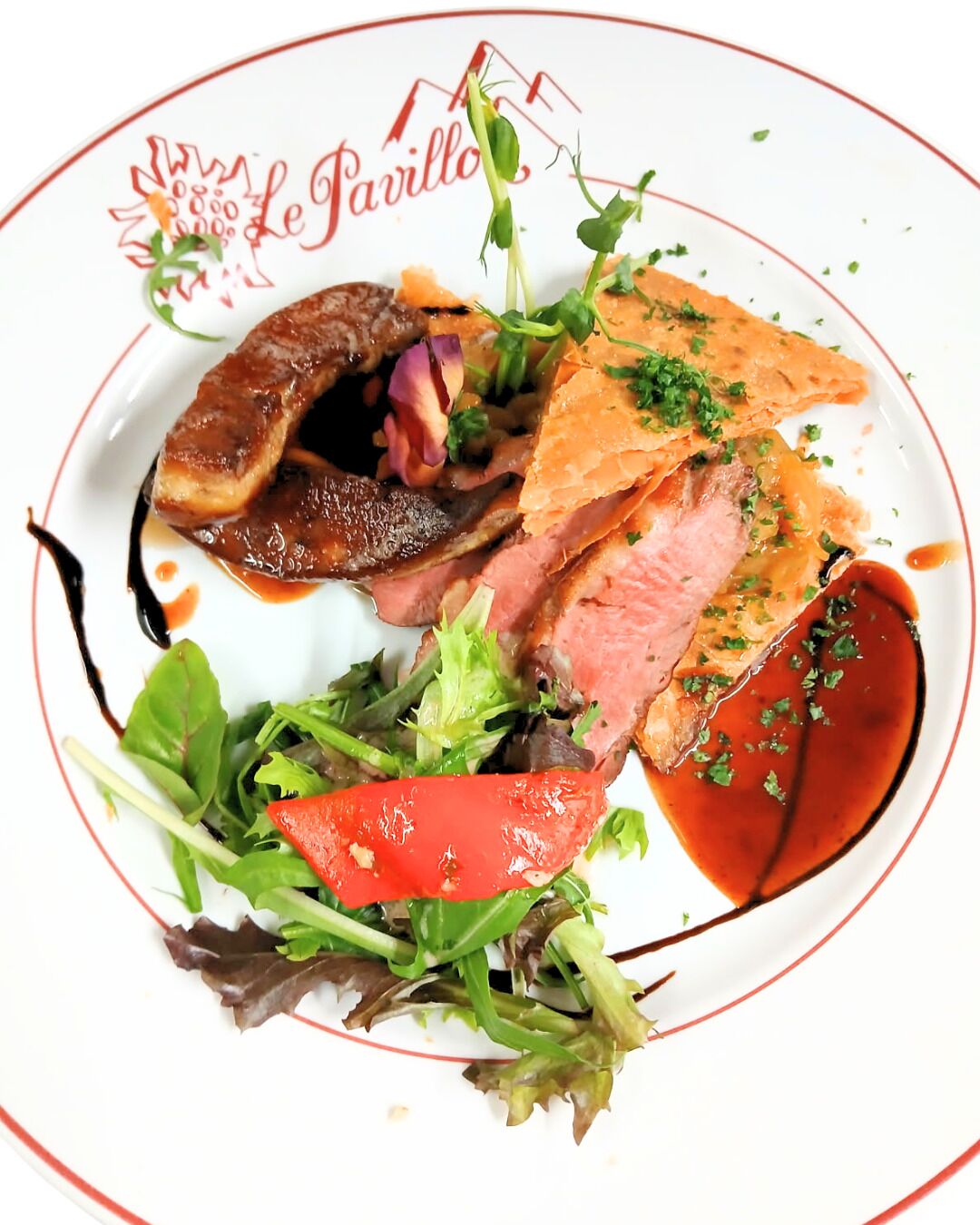 A plate of food with various meats, vegetables, and a sauce.