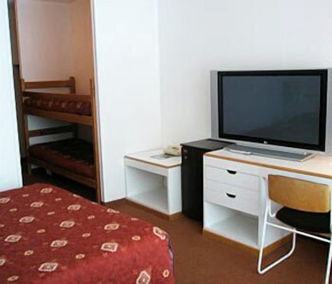 Una habitación con literas, un escritorio con computadora y una silla.