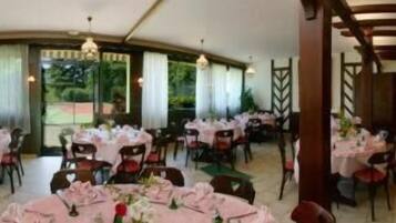 Un espace repas avec des tables rondes disposées pour accueillir plusieurs personnes, chaque table étant recouverte d’une nappe blanche et entourée de chaises rouges.