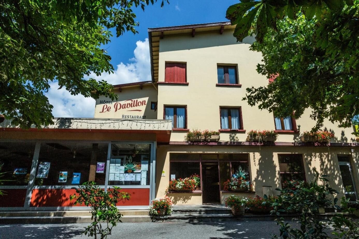 Un edifici de dues plantes amb un rètol que diu “Hôtel Le Pavillon Restaurant”. 