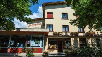 Un edifici de dues plantes amb un rètol que diu “Hôtel Le Pavillon Restaurant”.