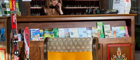 Un mostrador de recepción con encimera de madera, una lámpara amarilla y un tablón de anuncios con varios objetos.