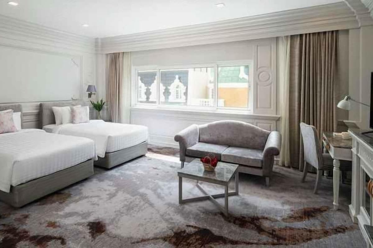 Ein Hotelzimmer mit zwei Betten, einem Sofa, einem Couchtisch und einem Fernseher.