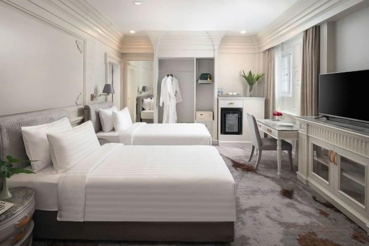 Ein Hotelzimmer mit zwei Betten, einem Schreibtisch, einem Fernseher und einem Badezimmer.
