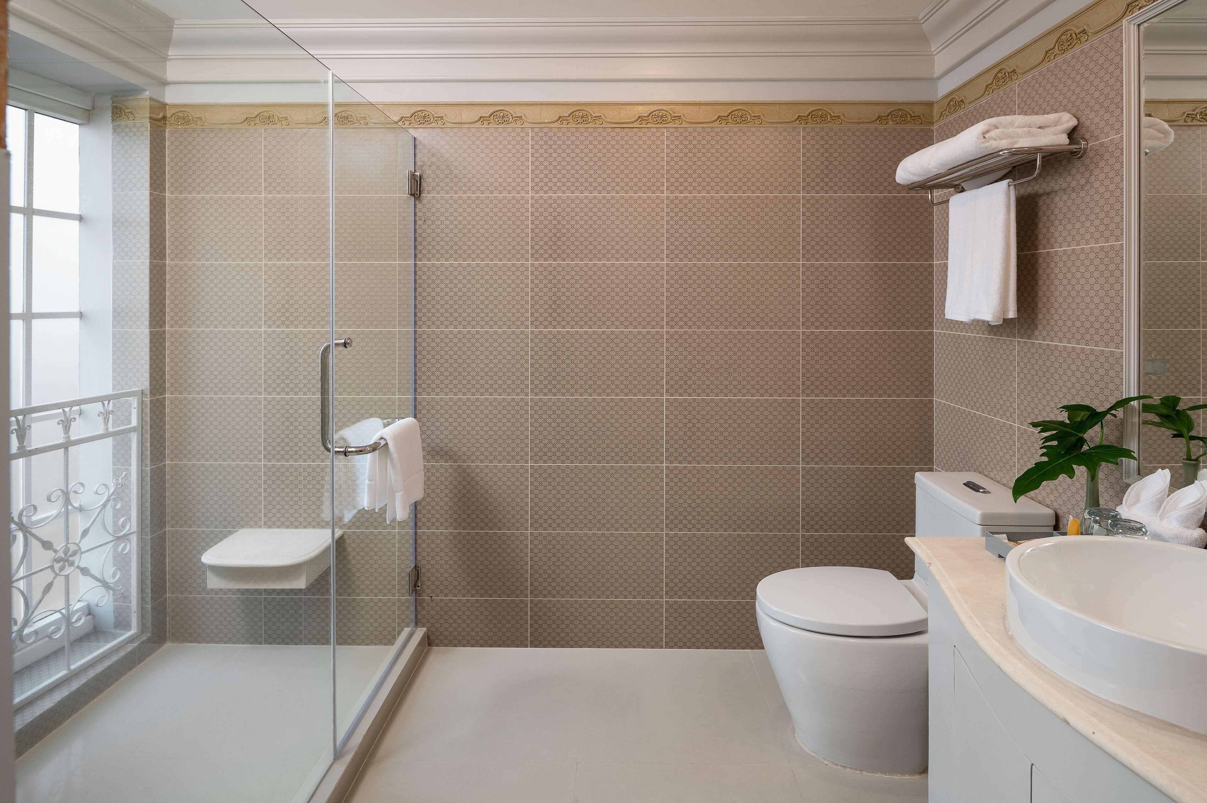 Un baño con ducha de vidrio, inodoro, lavabo y perchero para toallas.
