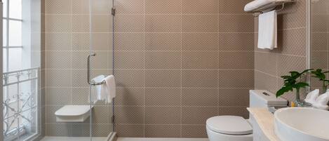 Un baño con ducha de vidrio, inodoro, lavabo y perchero para toallas.