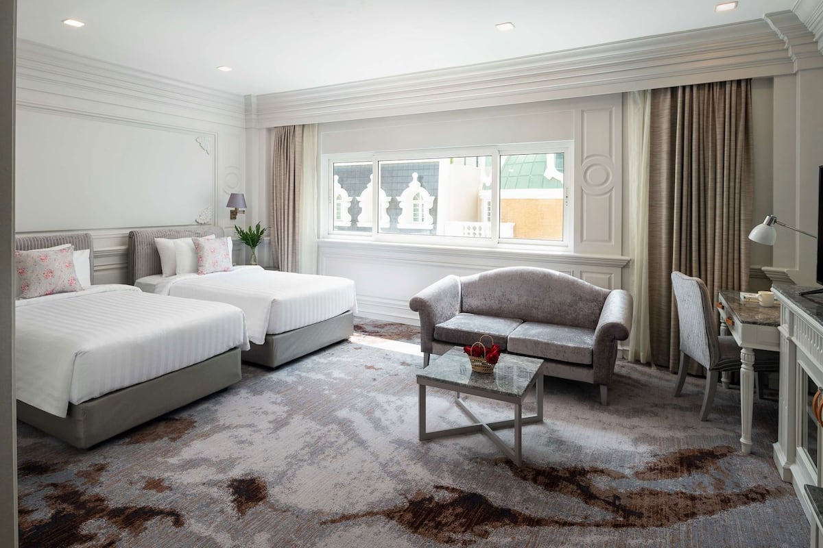 Une chambre d’hôtel avec deux lits, un canapé, une petite table et un téléviseur.