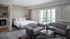 Een hotelkamer met een bed, twee sofa's, een salontafel en uitzicht op de stad.