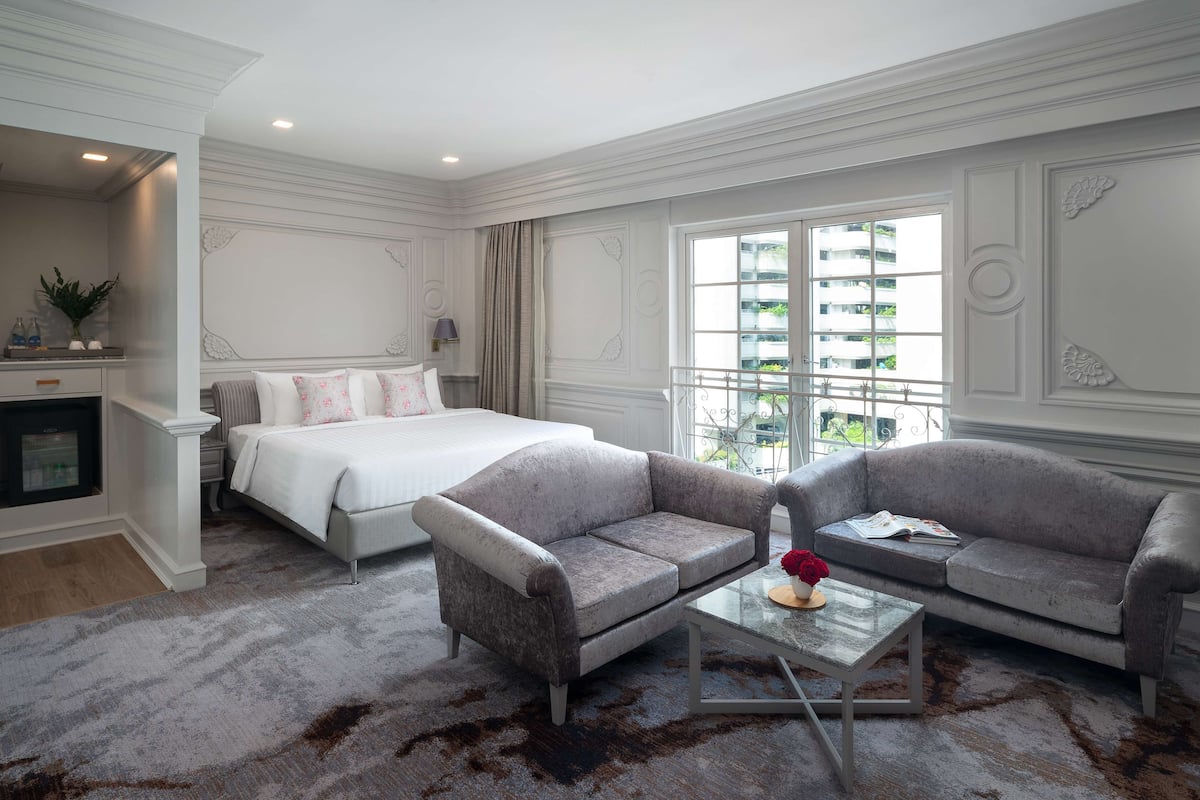 Une chambre d’hôtel avec un lit, deux canapés, une table basse et une vue sur la ville.