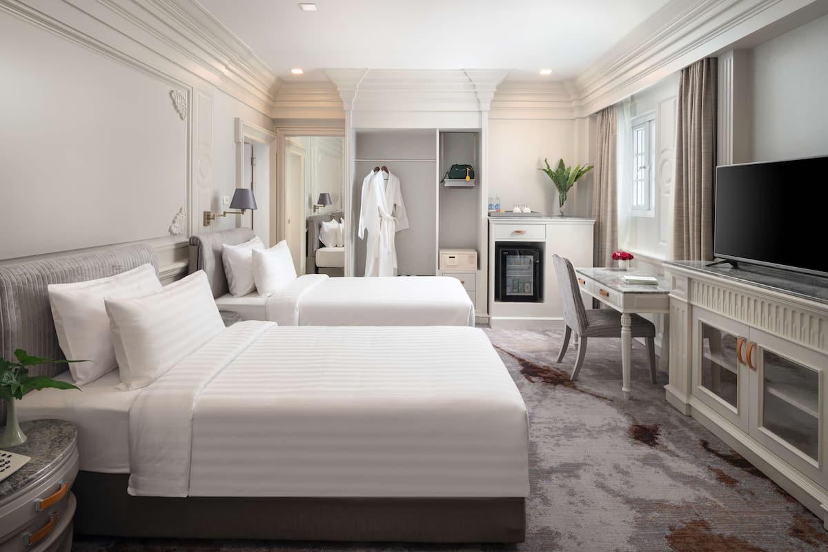 Une chambre d’hôtel avec deux lits, un bureau, une télévision et un minibar.