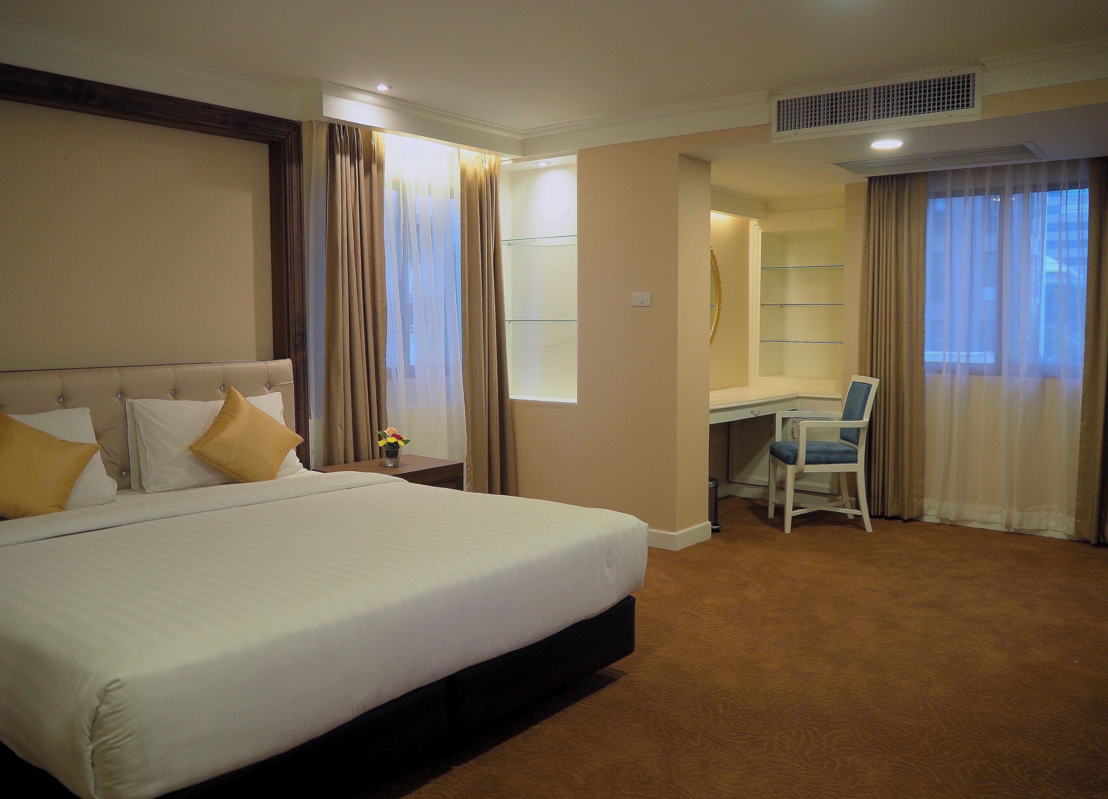 A hotel room with a large bed, a desk, and a chair.