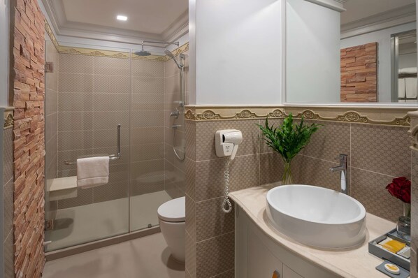 Un baño con ducha envuelta en vidrio, inodoro, lavabo con espejo y perchero para toallas.
