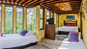A room with two beds, large windows, a television, and a painting on the wall. - Hotel Casa del Parque (Antigua Guatemala)