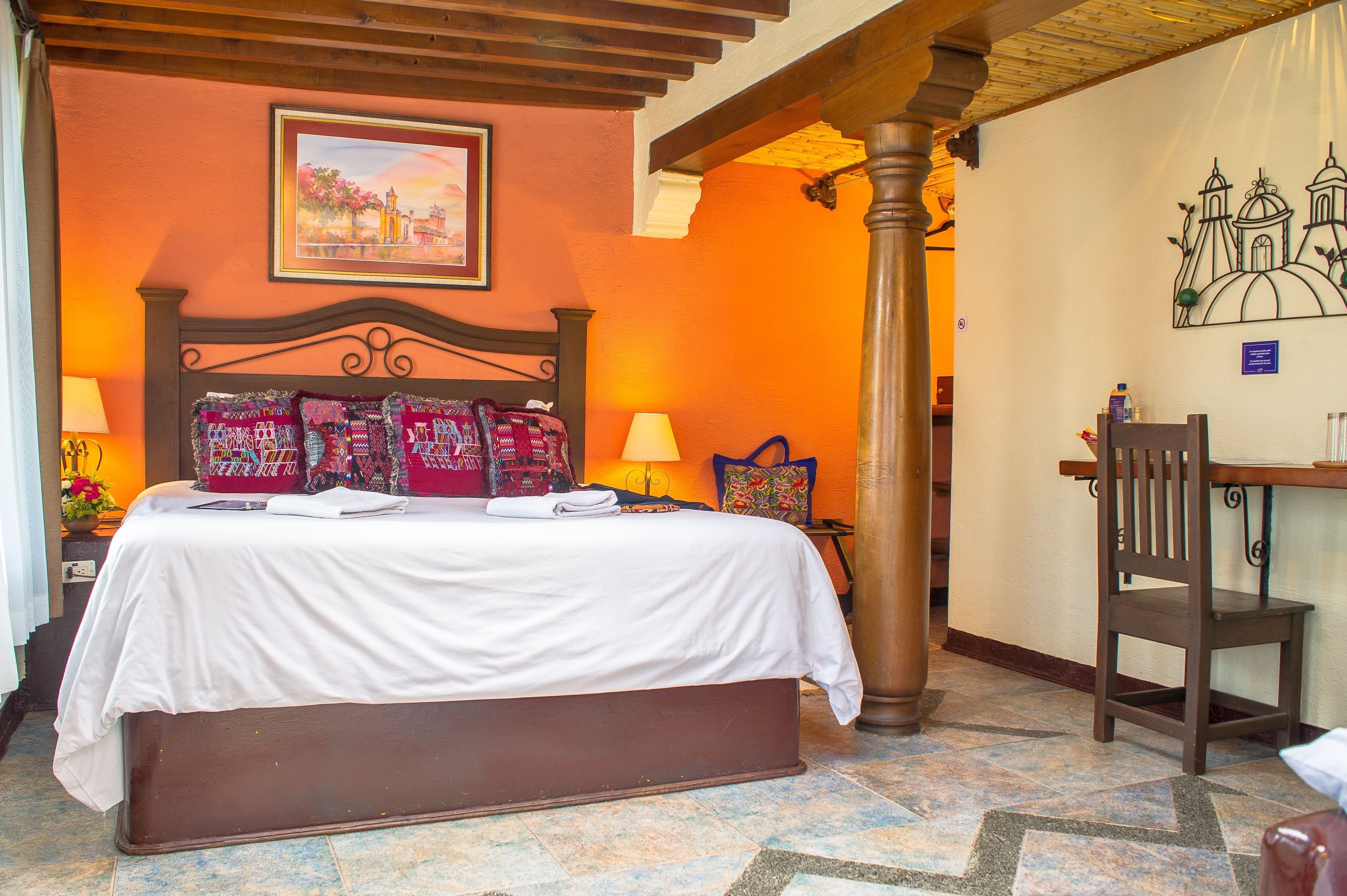 Une chambre d’hôtel avec un grand lit, une tête de lit en bois, un bureau et une chaise.