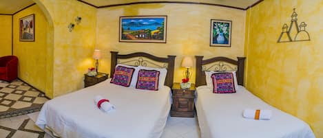A hotel room with two beds, a red chair, and artwork on the walls.