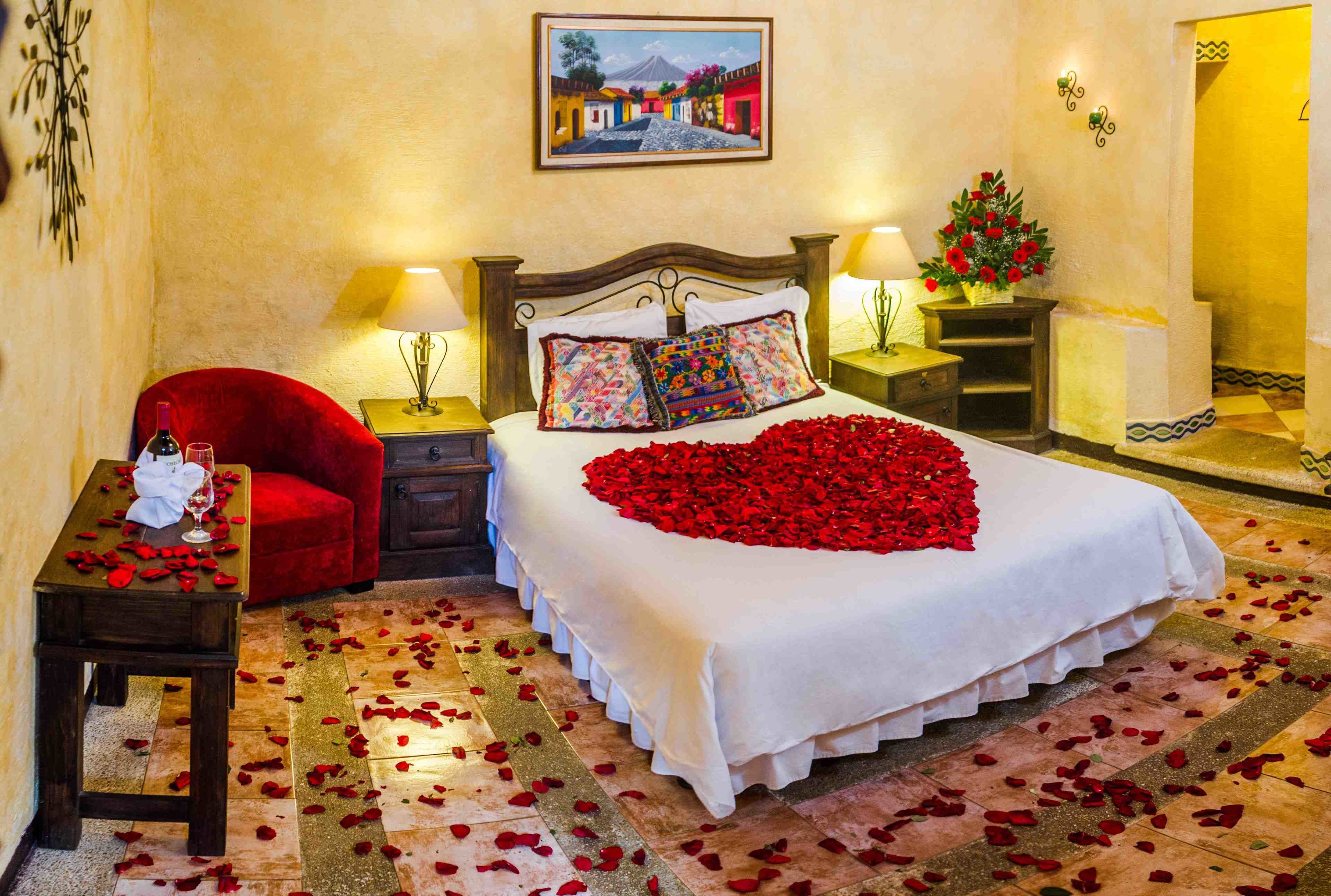 Une chambre d’hôtel avec un lit, deux tables de chevet, une chaise rouge et un tableau accroché au mur.