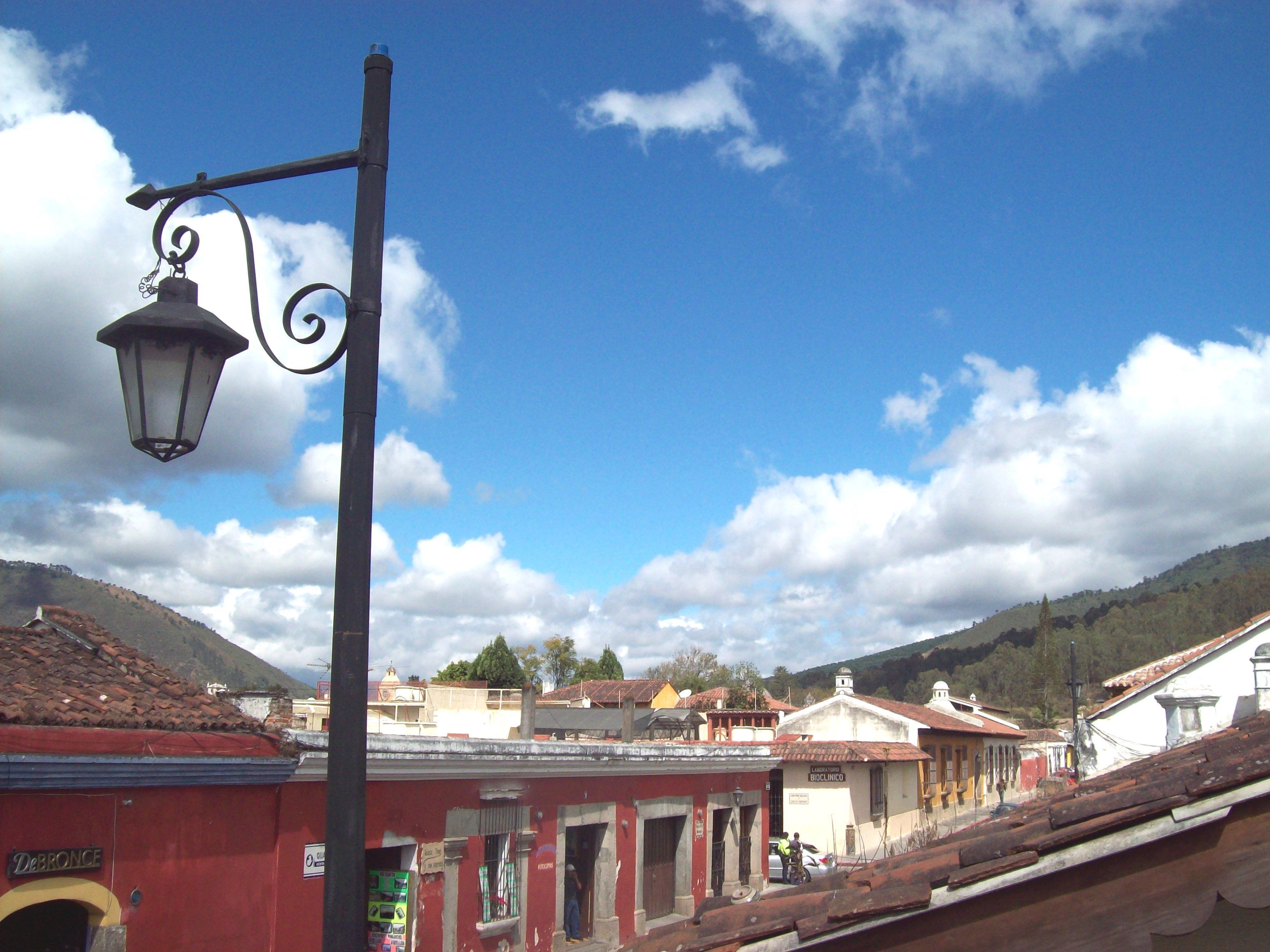 Una calle con edificios, una farola y un cielo azul despejado con nubes.