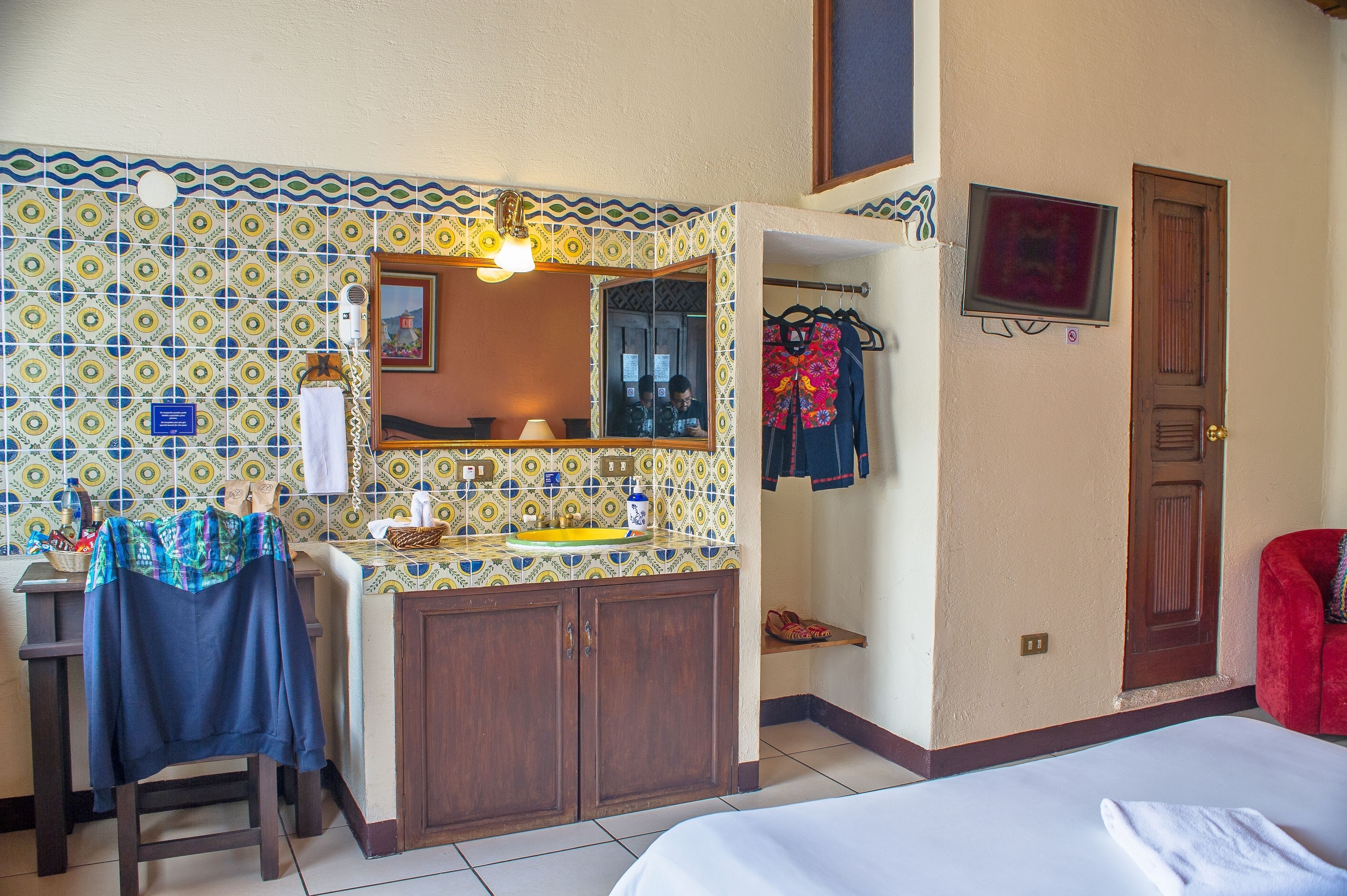 Een badkamer met betegelde spatwand, een wastafel, een spiegel en een douchegedeelte.