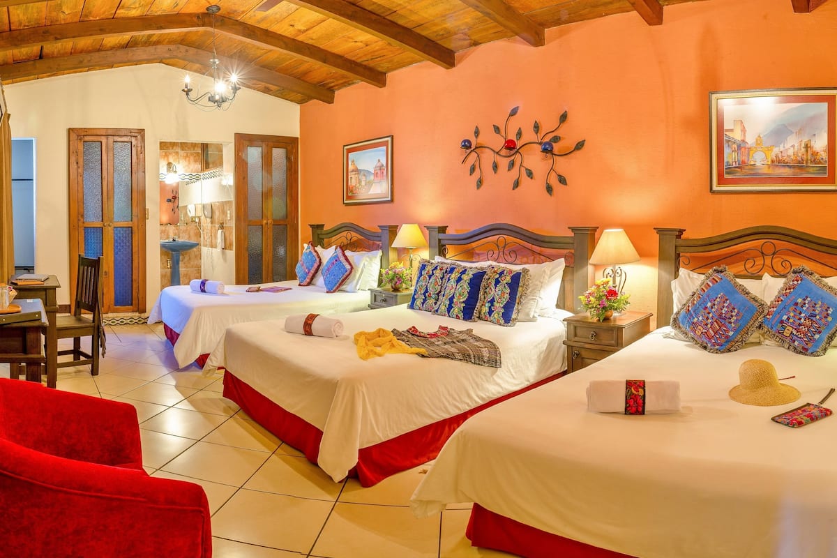 Une chambre d’hôtel avec deux lits, des têtes de lit en bois et une chaise rouge.