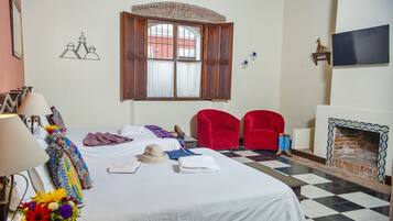 A hotel room with a bed, a window with curtains, a fireplace, and a checkered floor.