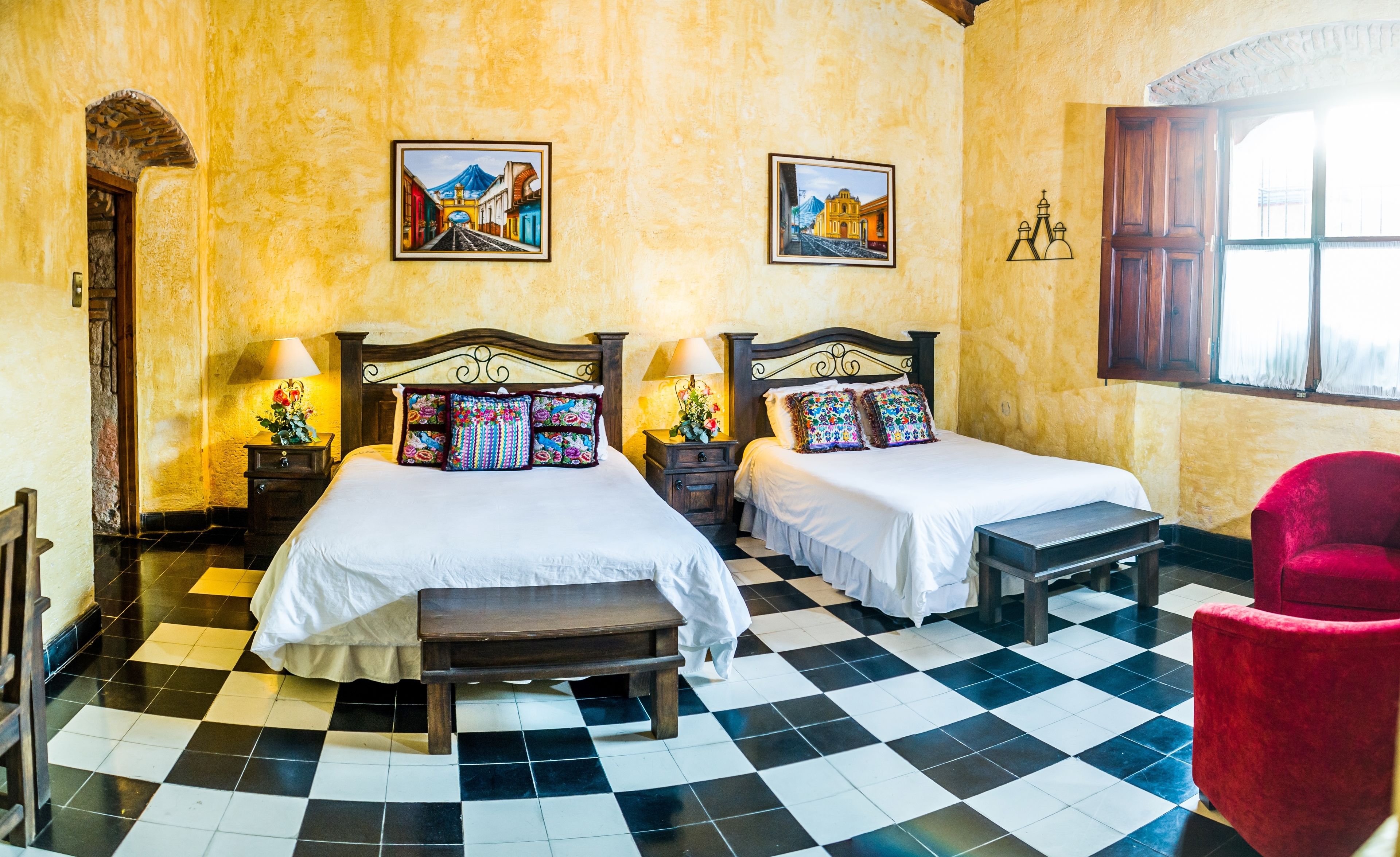 Habitación de hotel con dos camas, piso a cuadros, muebles de madera y dos cuadros en la pared.