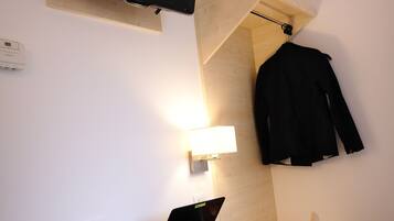 A modern room with a wooden desk, a laptop, a smartphone, a chair, a TV, and a jacket hanging on the wall.