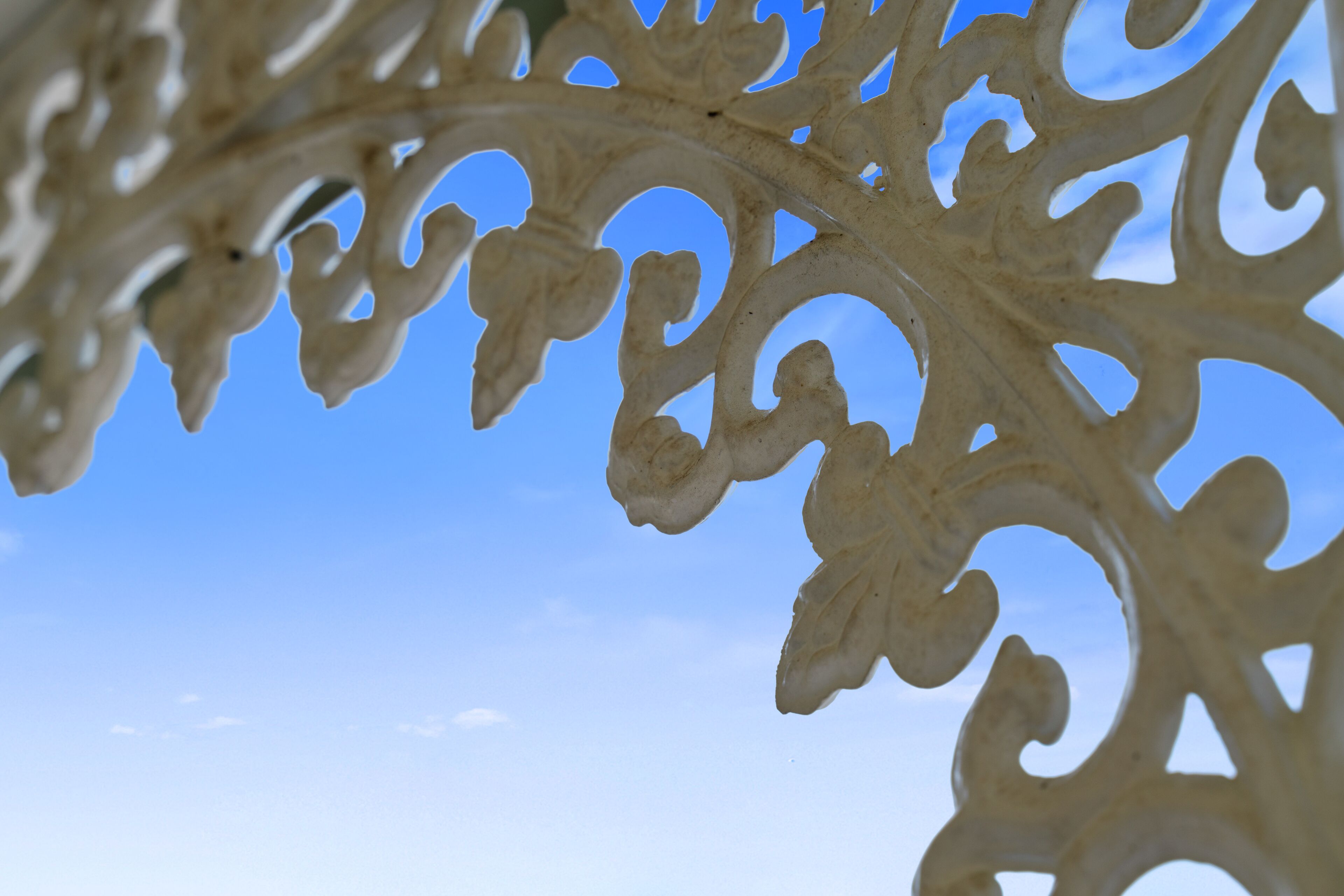 A close-up of a decorative metal structure with intricate cut-out patterns against a clear sky.