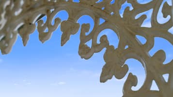 A close-up of a decorative metal structure with intricate cut-out patterns against a clear sky.