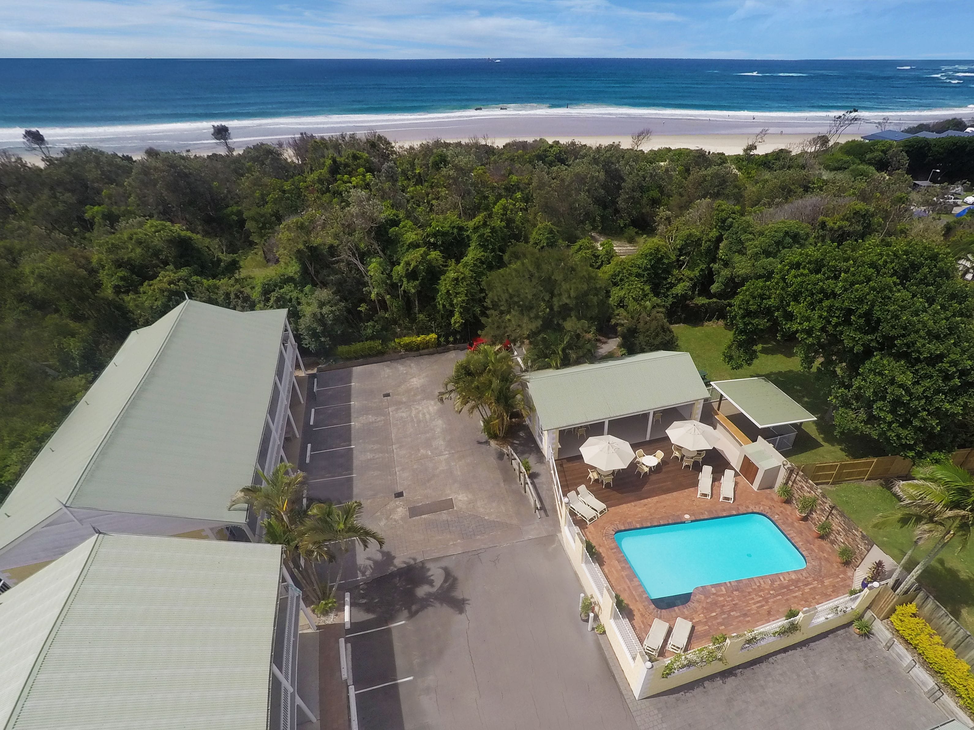 An aerial view of a property with a swimming pool, lounge area, and a view of the beach.