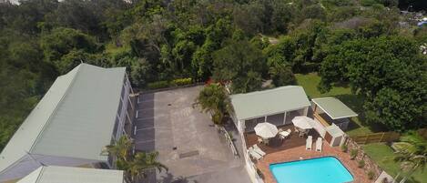 An aerial view of a property with a swimming pool, lounge area, and a view of the beach.