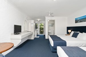 Habitación de hotel con cama, escritorio, televisión y vistas al balcón.