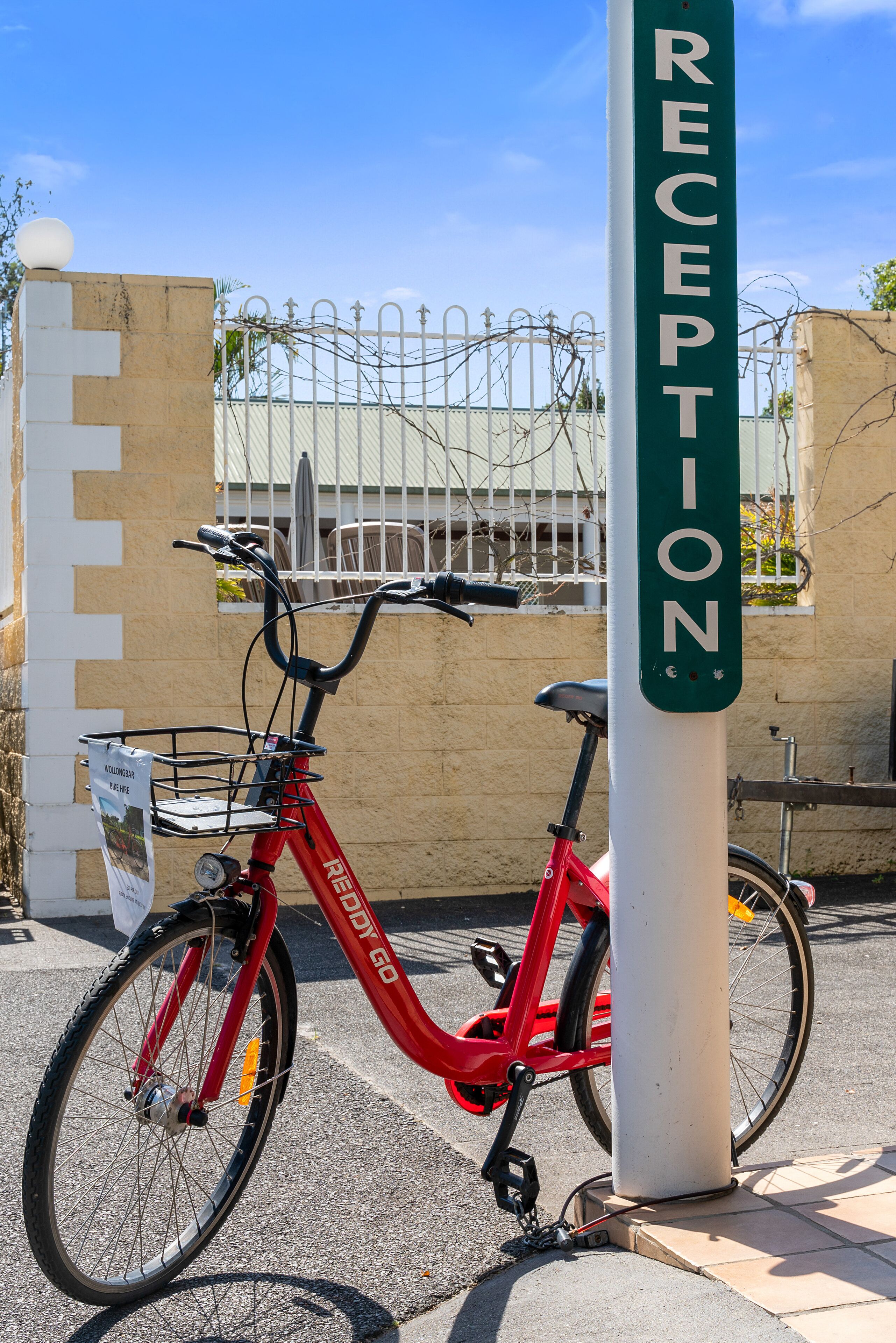 A red bicycle parked next to a reception sign.
