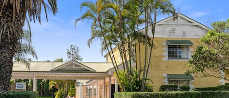 A building with a covered entrance, palm trees, and a sign indicating entry and off-street parking.