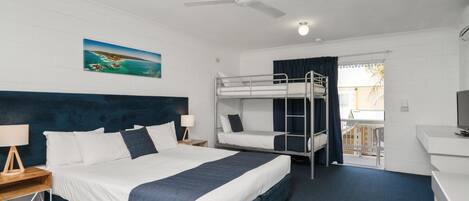 Ein Hotelzimmer mit Etagenbett, Schreibtisch, Stuhl, Deckenventilator und einem Bild an der Wand.