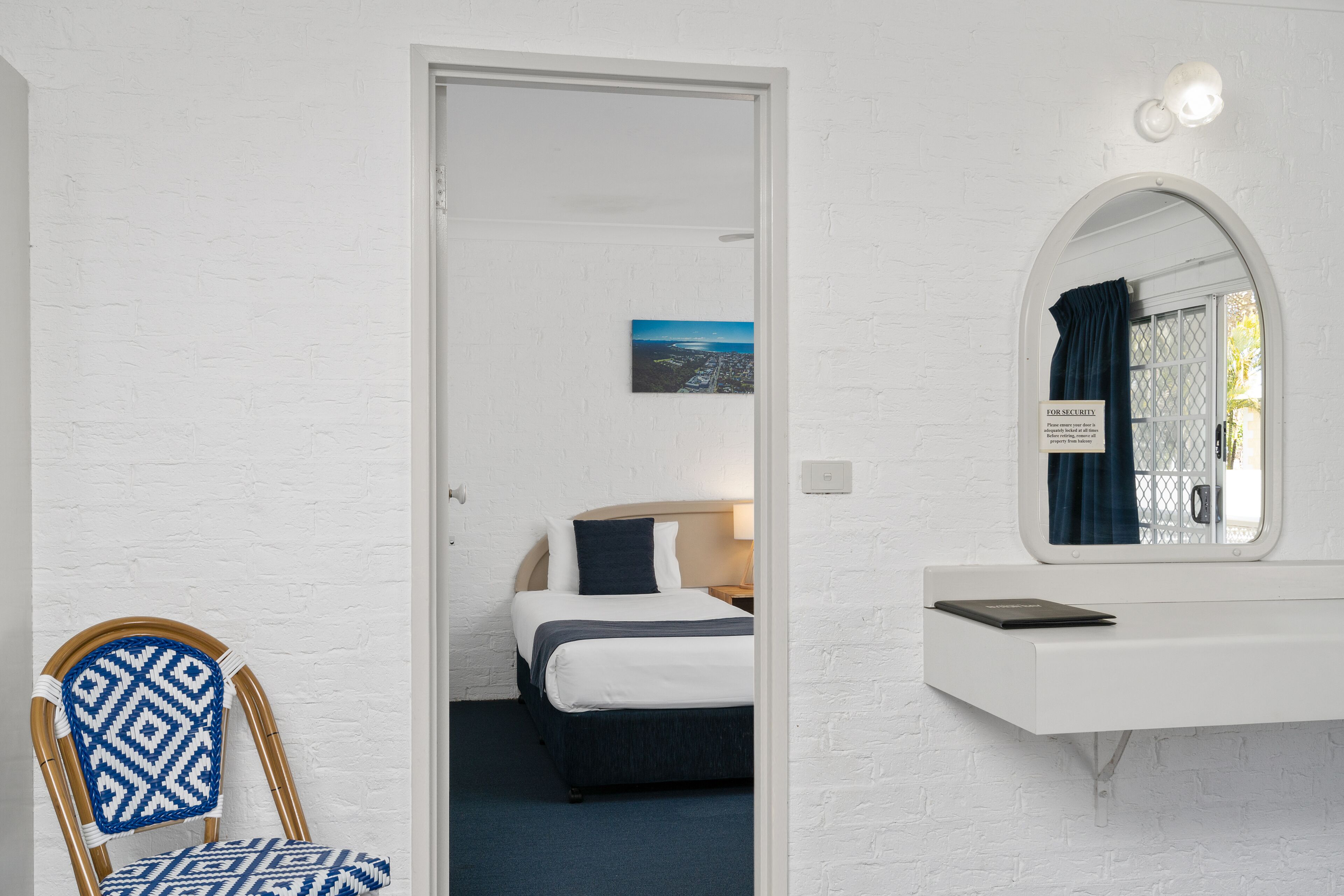 Habitación de hotel con cama, una silla, un escritorio y un espejo.