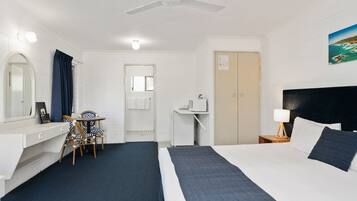 A hotel room with a bed, desk, chair, and a ceiling fan.