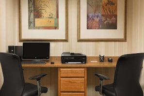 Un espacio de trabajo con computadora de escritorio, impresora y dos sillas de oficina.