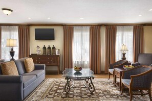 A living room with a sofa, armchairs, a coffee table, and a television.